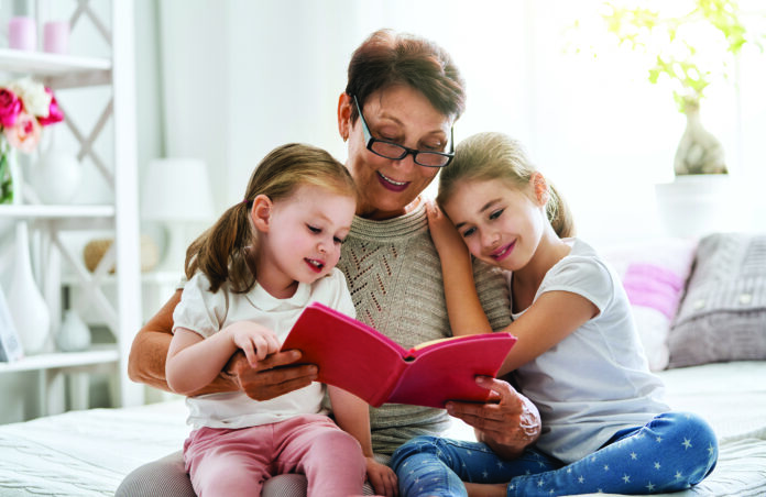 Grandmother,Reading,A,Book,To,Her,Granddaughters.,Family,Holiday,And